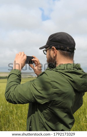 Adult man take a picture by smartphone outdoor in field