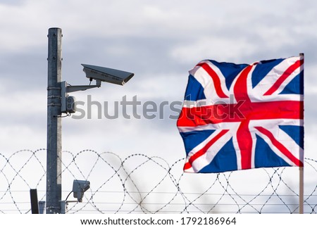 Flag of the United Kingdom  with surveillance camera and barbed wire, concept picture