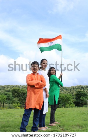 3 Indian students  or children holding or waving Tricolour with greenery in the background, celebrating Independence or Republic day Royalty-Free Stock Photo #1792189727