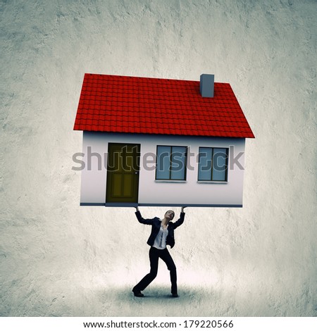 Young businesswoman lifting huge model of house above head