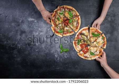Hand taking pizza slice on dark table