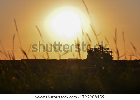 Silhouette of grain storage silo facilities at orange sunset view. 
Selective focus.