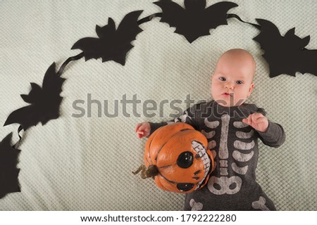 My first Halloween. Small child and pumpkin. Autumn concept, halloween, bats, pumpkins, newborn close-up and copy space.
