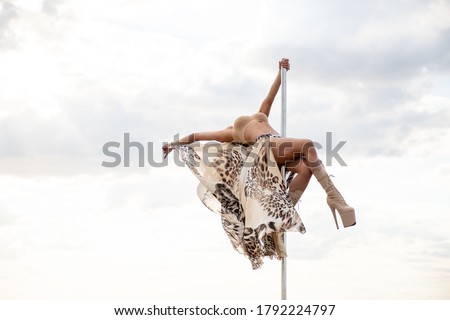 Slim Woman at the beach with long fabric. Sky background at the summer. Pole dancer on the nature. Female pole dancer against sea and sky.