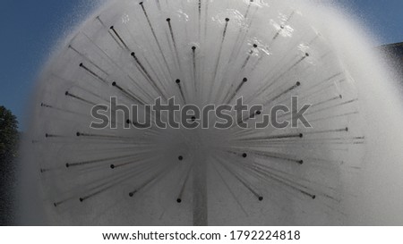 dandelion fountain with small drops and blue sky in the background