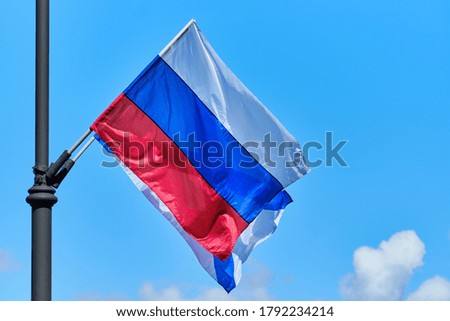 The Russian flag develops from the wind against the background of the sky.