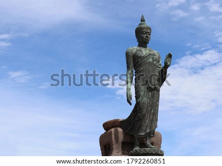 Front of Buddha statue is standing isolated on blue sky and white cloud background closeup at Phutthamonthon park, Nakhon Pathom,Thailand.