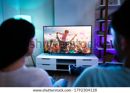 Family Couple Watching TV Or Movie On Couch Royalty-Free Stock Photo #1792304128