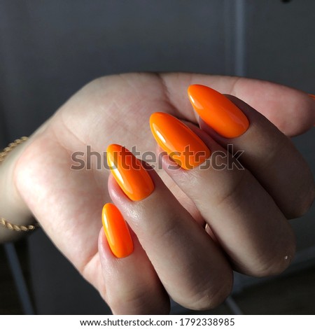 Orange manicure. Hands of a woman with orange manicure on nails.Manicure beauty salon concept. Empty place for text or logo.