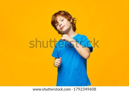 redhead boy tilted his head to one side yellow background studio grin 