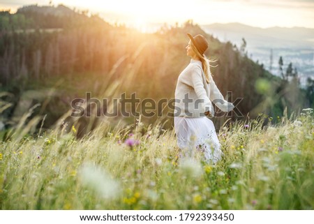 Portrait happy woman enjoying sunset stay on the green grass on the forest peak of mountain. Fresh air, Travel, Summer, Holidays, Journey, Trip, Lifestyle.