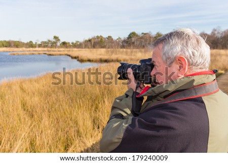 Senior man taking photos in a nature reserve
