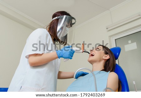 Woman dentist using photopolymer lamp in teeth treatment