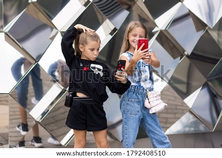 Happy girlfriends make selfie. Cute girls 10 years old enjoying a walk in the city