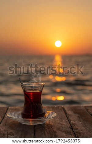 Turkish tea in a glass on wooden table by the sea. sunset view at sea