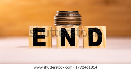 The concept of the word end on wooden cubes with coins on a white wooden background. Business concept.