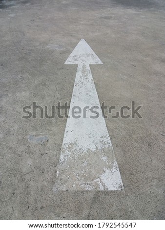 Arrow sign indicating the direction straight ahead on a concrete road as a background.