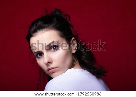 upset woman in a light T-shirt on a red background
