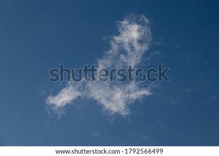 A singular soft white cloud on an otherwise blue sky. Royalty free stock photo.