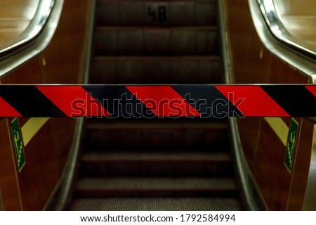 Closed escalator in metro. Bottom view. Repair of escalators, no entrance, closed passage. Red and black stripes on forbidding barrier. Escalator stopped. Space for your label and advertising