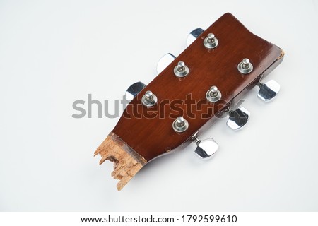 Broken guitar neck on a white background with copy space. Broken acoustic guitar headstock, close-up. Guitar repair and service  Royalty-Free Stock Photo #1792599610