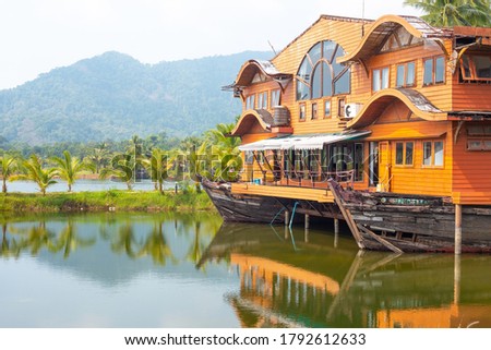 Tropical landscape. Wooden house in the form of a boat on the ocean with a view of the mountains. Travel and tourism in Asia