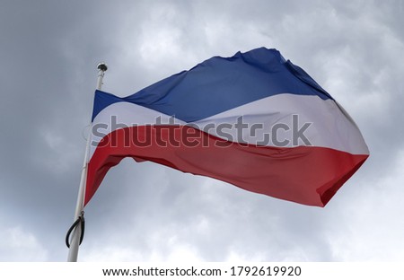 Schleswig Holstein flag at a flagpole moving in the wind against the sky