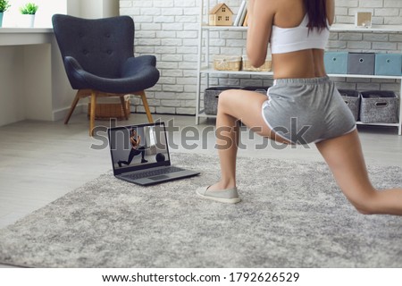 Online fitness at home. The girl does exercises watching the video course the trainer has a laptop at home. Royalty-Free Stock Photo #1792626529