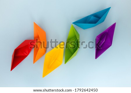 Colored paper boats with the colors of the rainbow on a light blue background