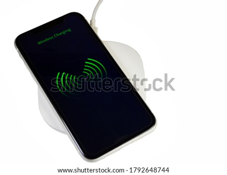 Smartphone charging on a wireless base with white background