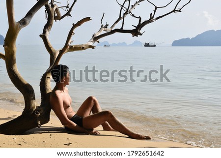 Handsome Asian man in swimwear get relax on the beach with out people after pandemic of Covid-19 had relieve in Thailand 