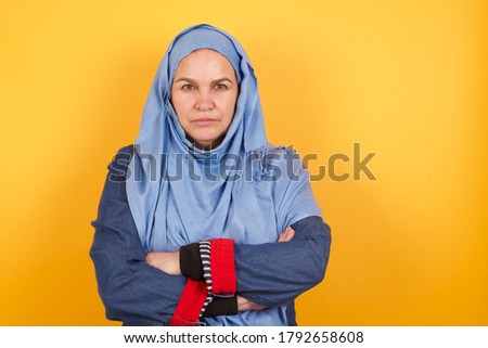 Picture of angry beautiful muslim woman standing isolated over bright background. Looking camera.