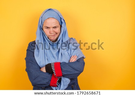 Picture of angry Caucasian muslim woman crossing arms standing isolated over background. Looking at camera.