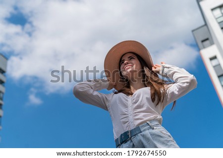 Portrait of a beautiful caucasian woman outdoors against a blue sky background. A girl wearing a hat and walking shorts on a hot summer day.