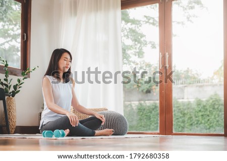 Shot of attractive healthy Asian woman doing meditation at home in living room Royalty-Free Stock Photo #1792680358