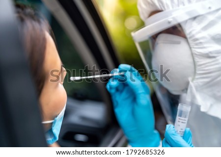 Portrait of asian woman drive thru coronavirus covid-19 test by medical staff with PPE suit by nose swab. New normal healthcare drive thru service and medical concept. Royalty-Free Stock Photo #1792685326