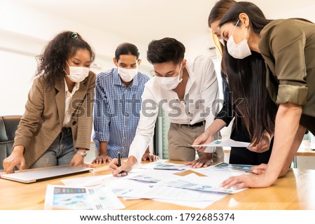 Interracial asian business team brainstorming idea at office meeting room after reopen due to coronavirus COVID-19 city lockdown. They wear face mask reduce risk to infection as new normal lifestyle. Royalty-Free Stock Photo #1792685374