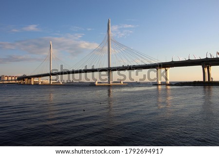 View of the cable bridge and the bay at sunset. Reflection of pylons and bridge pillars in the water