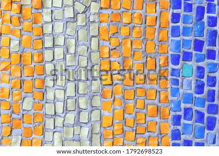 The wall is lined with a mosaic of blue, orange, beige as a background, texture, pattern.