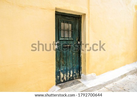 Old door of residential building in Plaka district, Athens, Greece. Plaka is tourist attraction of Athens. Traditional house with yellow wall and grunge door on vintage street in Athens city center.