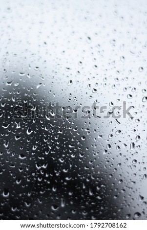 Raindrops dripping on glass out of soft focus with blurred background