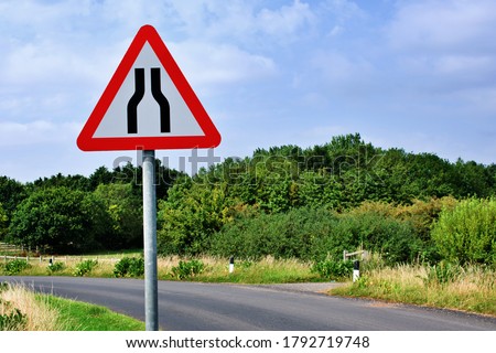 UK road sign  Road narrows on both sides against a blue cloudy sky. Royalty-Free Stock Photo #1792719748