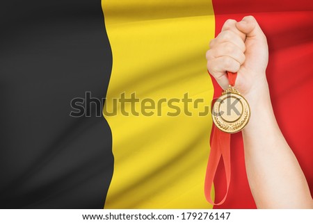 Sportsman holding gold medal with flag on background - Kingdom of Belgium