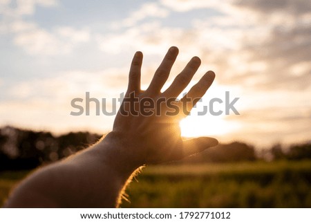 Hand stretching to the setting sun
