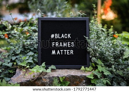 "Black frames matter" sign on black wooden letterbox in natural background. Selective focus.