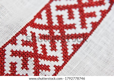 embroidery with a cross with red nicknames on linen