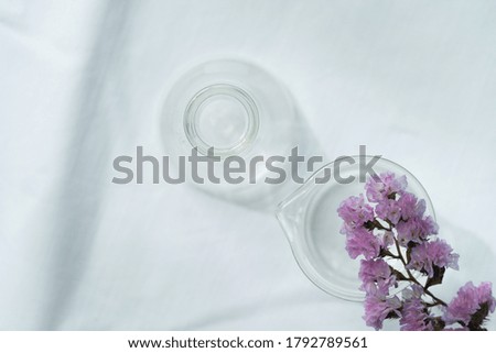 summer soft purple flower from the top of glass science flask and beaker for  natural cosmetic research fabric on white fabric background