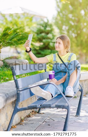 Young woman takes coffee in the park, relaxing, while having her picture taken. Lifestyle, happiness, woman.