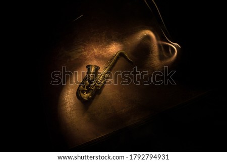 Music concept. Saxophone jazz instrument. Alto gold sax miniature with colorful toned light on foggy background. Saxophone music instrument in lowlight. Selective focus