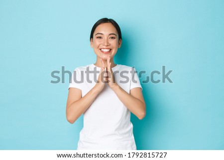 Charming happy asian female in white t-shrit smiling satisfied, clapping hands, congratulate person with win, praising good work, well done, compliment someone achievement, blue background
